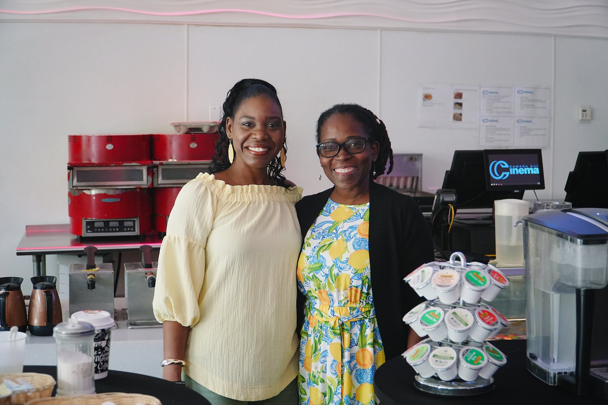 Two people smile beside the coffee station.