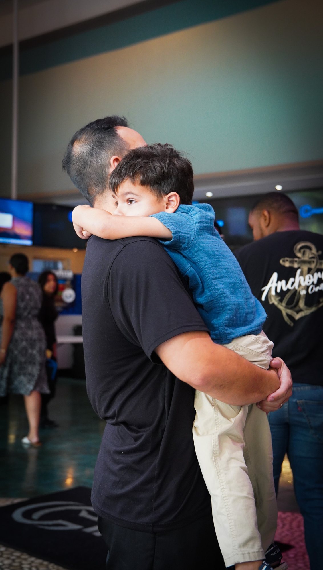 An adult holds a young child in the church lobby.