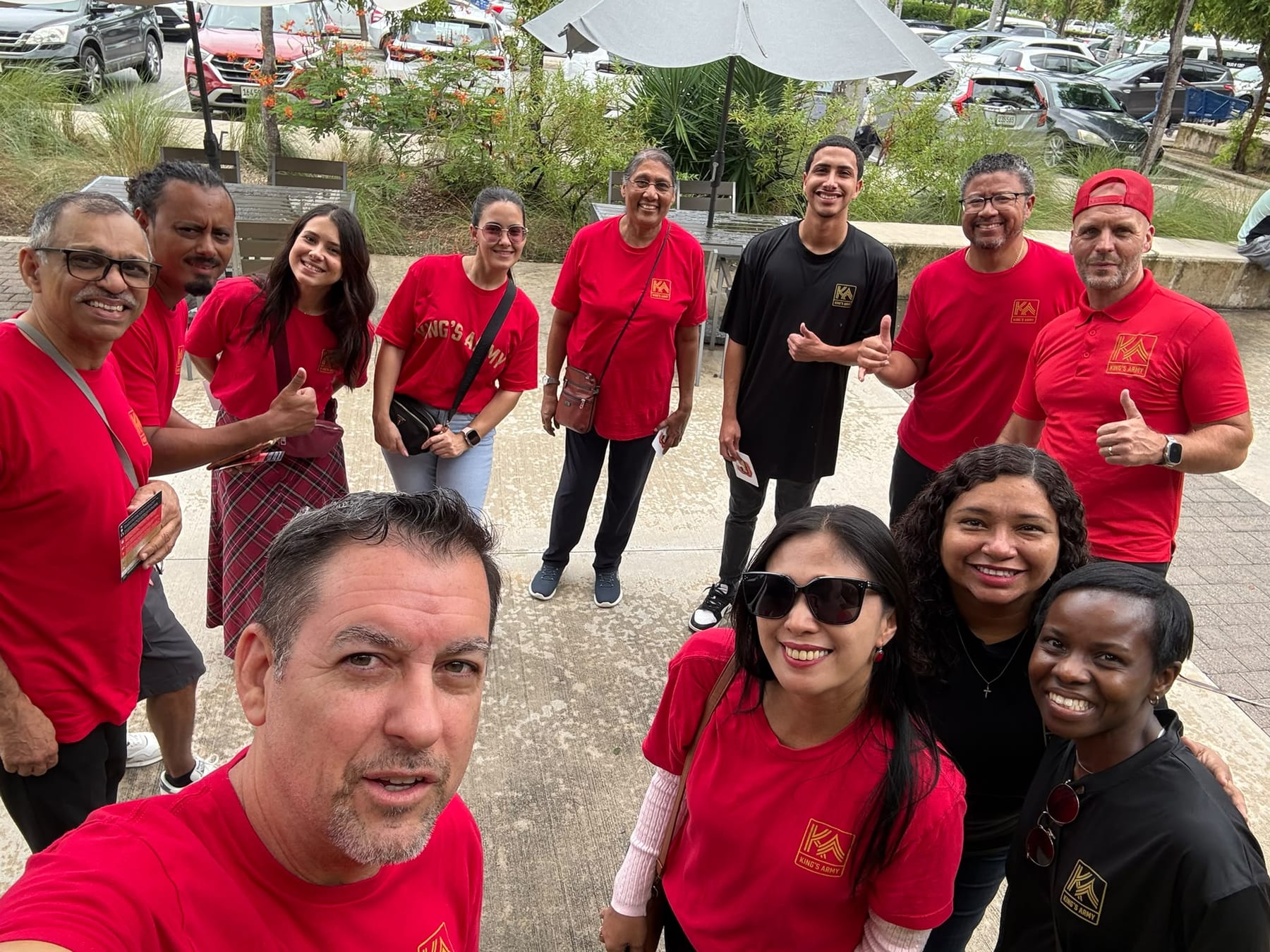 King’s Army team members gather outdoors in red and black shirts.