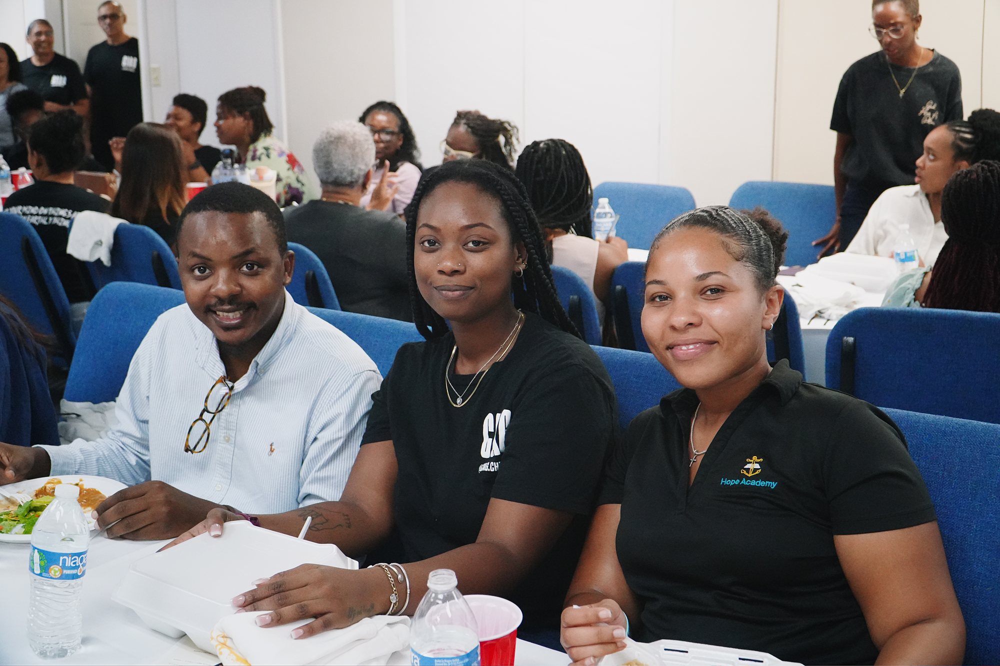 Three people sit together at a shared meal during a church gathering.