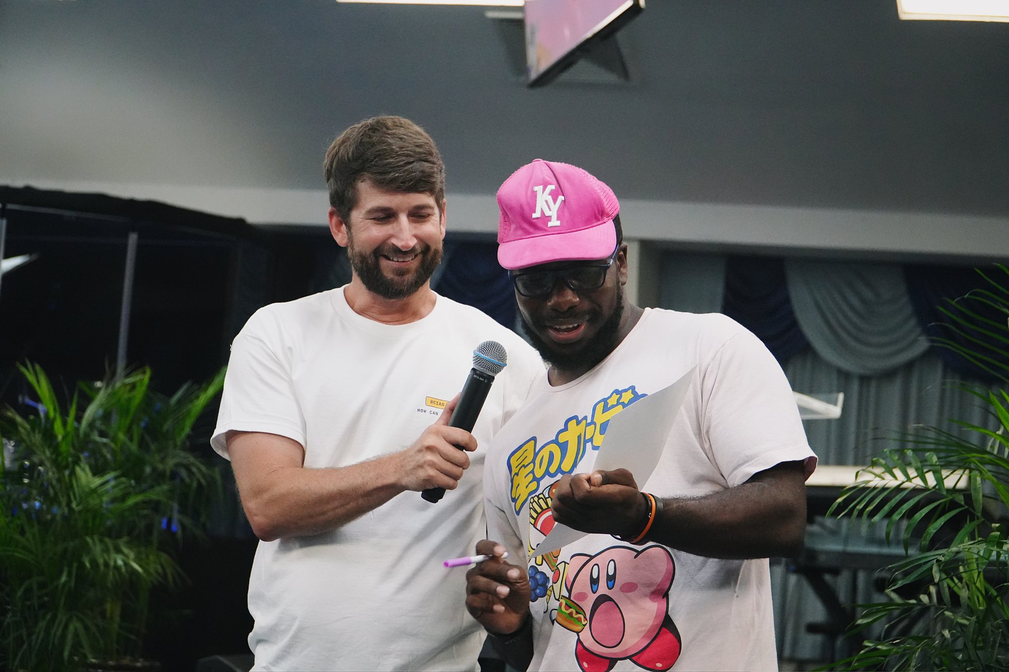 Two people share a microphone and read from a sheet during a church gathering.