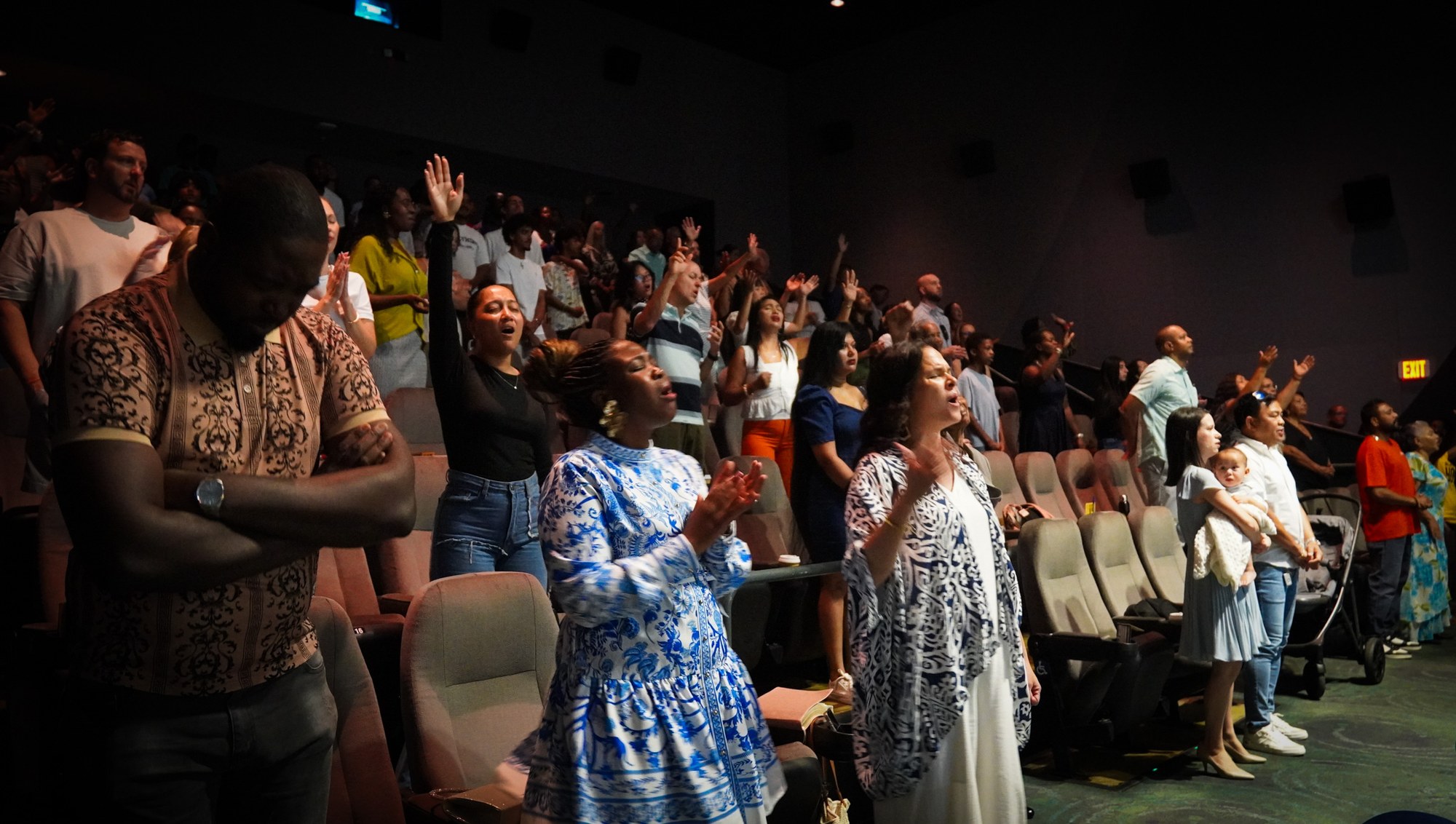 People stand together during worship in the auditorium.