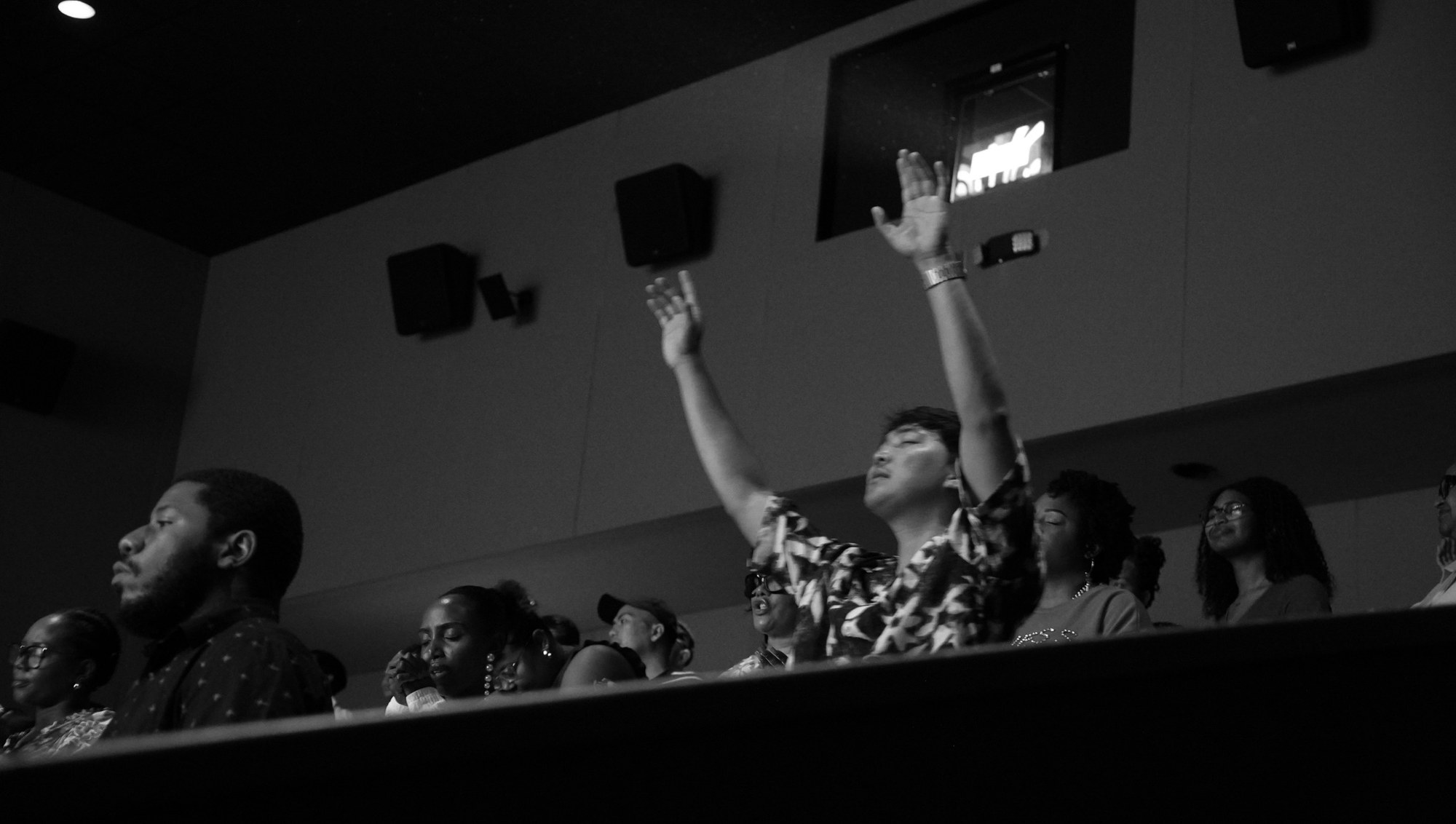 People worship with hands raised during a Sunday gathering.