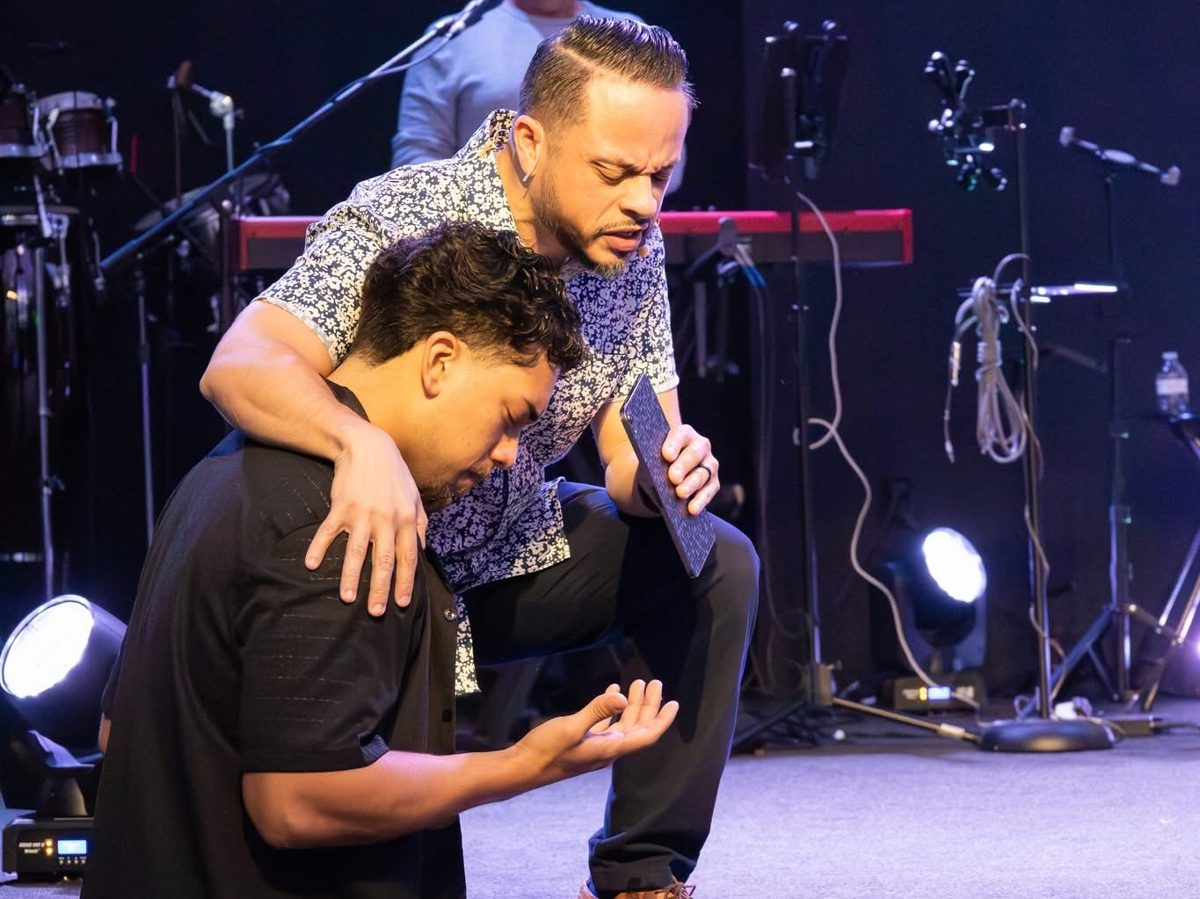 Pastor Dennis Feliciano praying over a young man at the altar