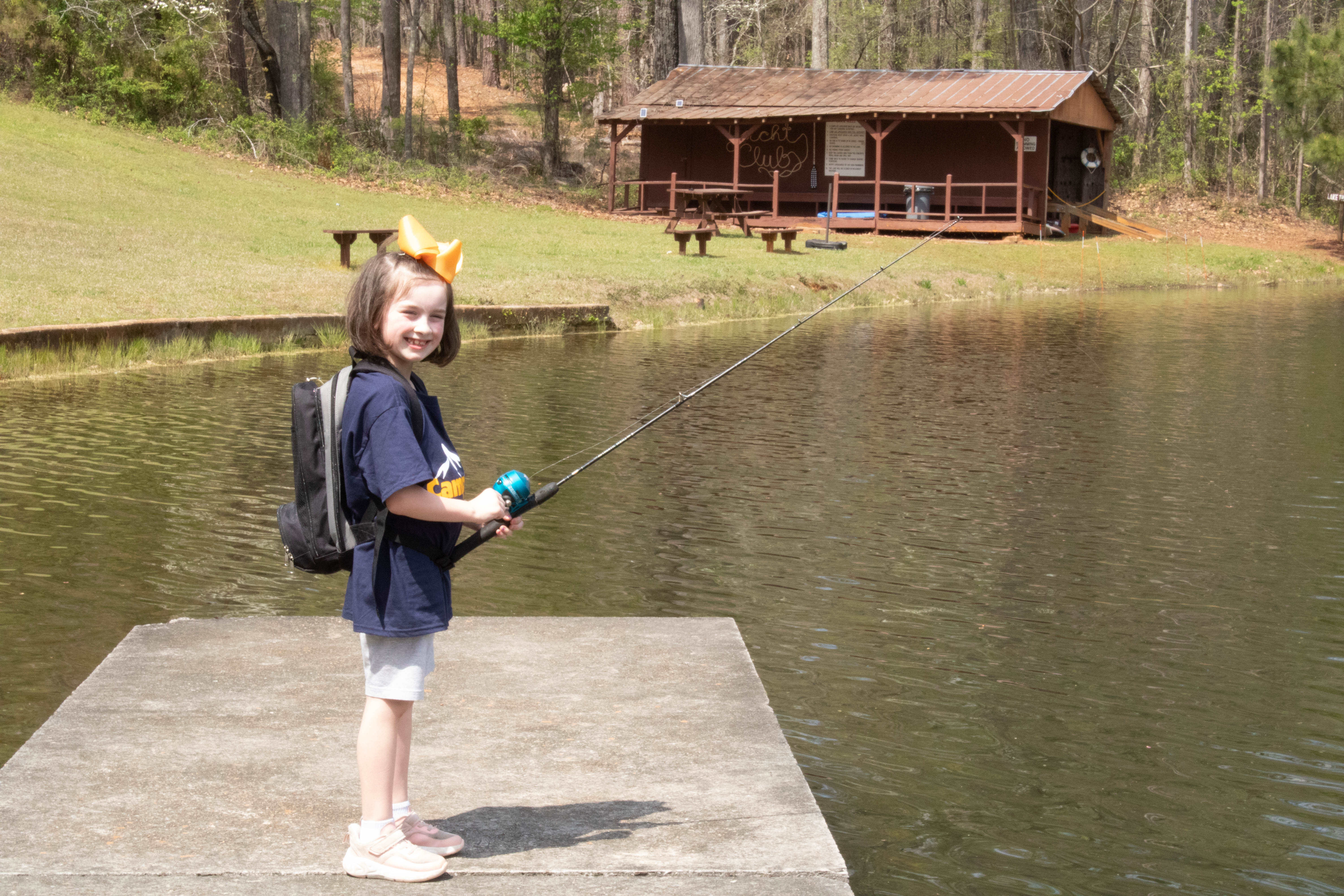 A young camper fishing off the dock on the main lake