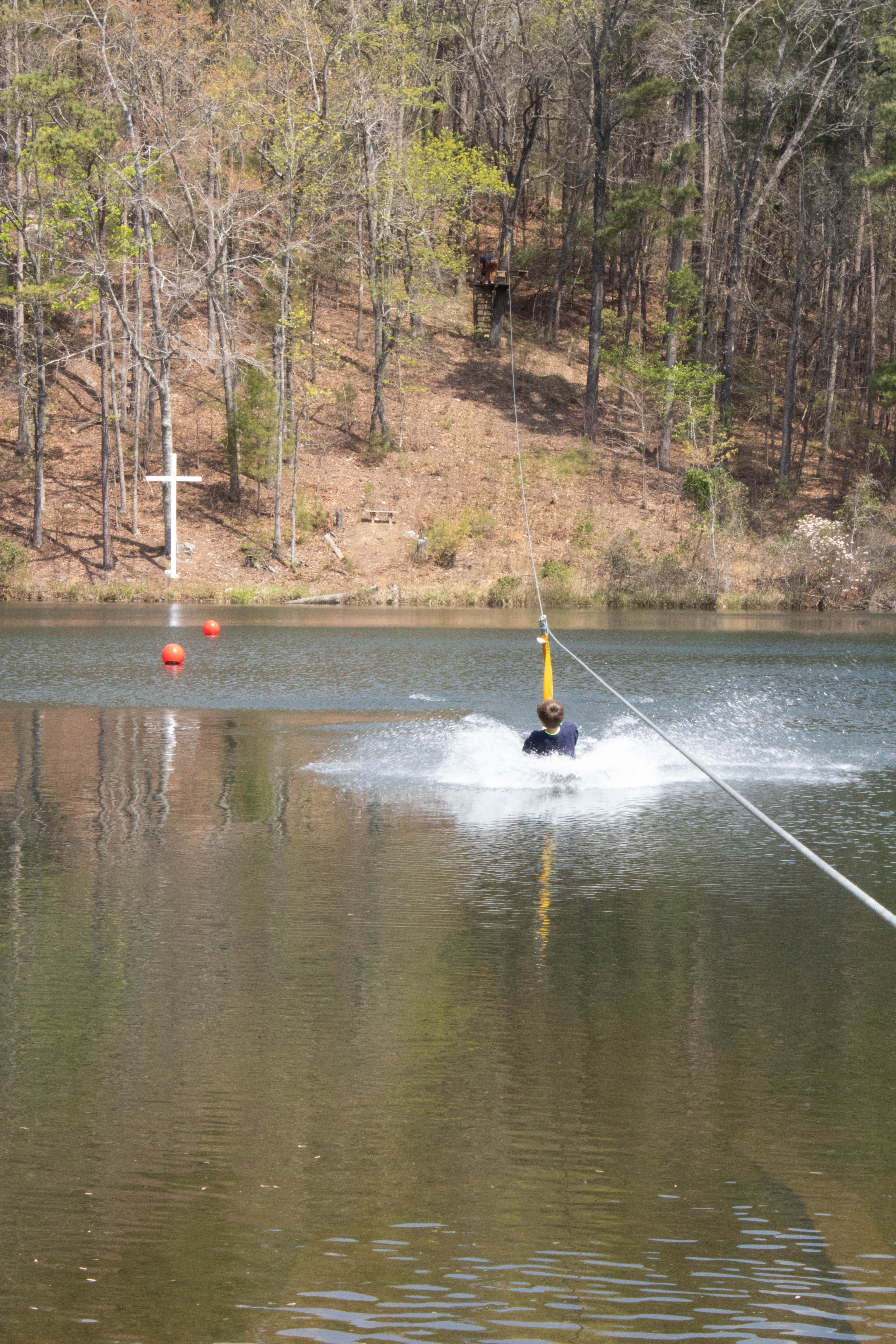 A camper splashing down on the water zip line